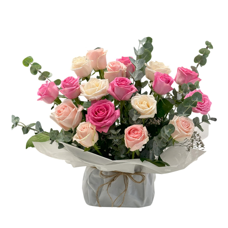 A bouquet of pink and cream roses with eucalyptus wrapped ina rustic paper.