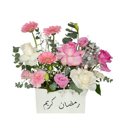 A white Ramadan Kareem gift box filled with pink and white roses, gerberas, lisianthus, and a silver lantern, creating an elegant Eid floral arrangement.