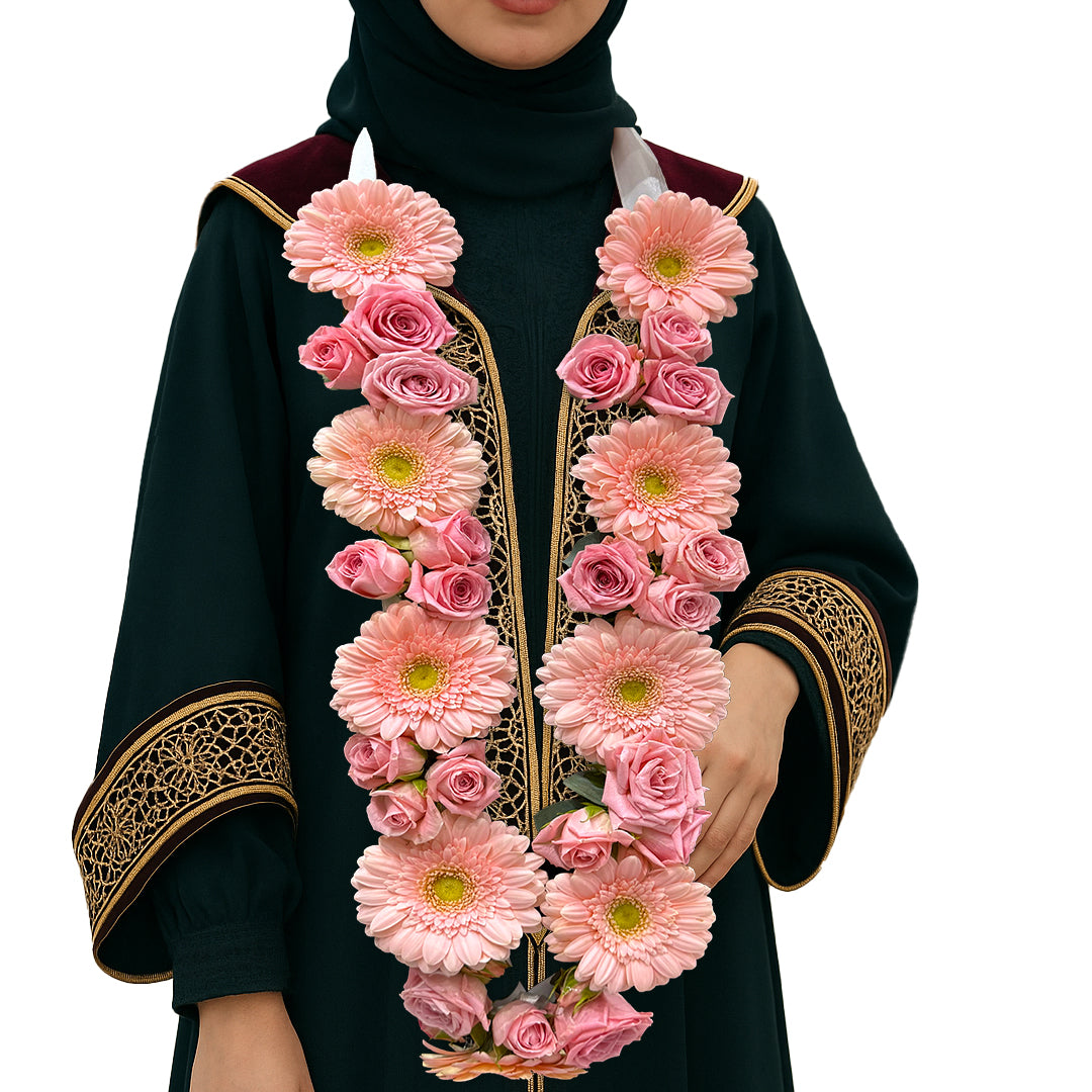 Pink gerbera and rose floral garland necklace on a female graduate in black and gold gown