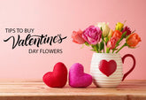 A vase with colorful roses on a wooden table with two heart-shaped decorations.