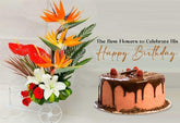 A floral arrangement with Bird of Paradise and anthuriums in a tricycle planter, next to a cake, with a "Happy Birthday" message.