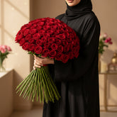 A large, dense bouquet of vibrant red roses with green stems, arranged in a round shape against a solid white background.