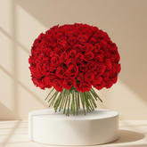 A large, dense bouquet of vibrant red roses with green stems, arranged in a round shape against a solid white background.