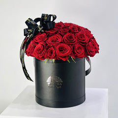 Black cylindrical box with red roses and black ribbons on a white background order from best place and feel the freshness