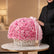 A large round arrangement of pink roses in a white wicker basket, tied with a pale pink ribbon,