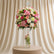 A large round floral arrangement in a tall clear glass vase, featuring pink, peach, cream, and white flowers with green foliage, displayed indoors against a light wall.