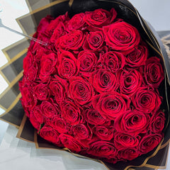 Bouquet of red roses wrapped in black paper on a light gray background new valentine flower design