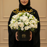 Bouquet of white flowers in a black container with Arabic text on a white background