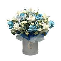 A beautiful blue and white floral arrangement in a hatbox with a "Baby Boy" topper, perfect for welcoming a newborn.