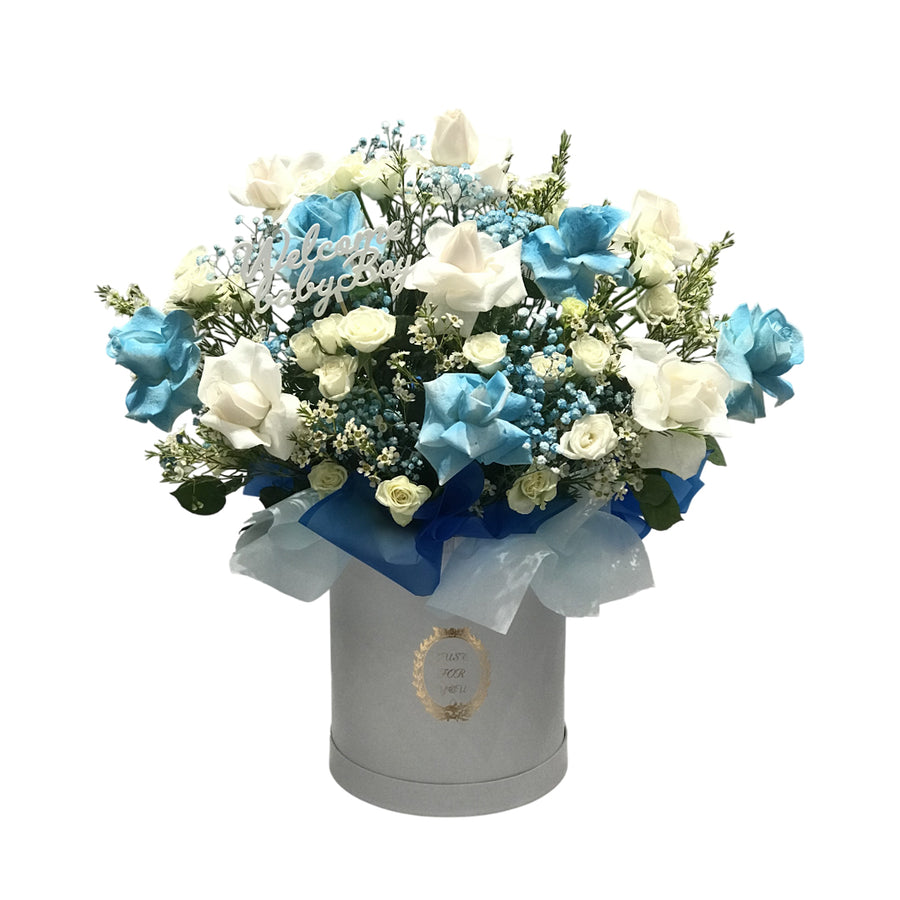 A beautiful blue and white floral arrangement in a hatbox with a "Baby Boy" topper, perfect for welcoming a newborn.