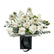  A black gift bag filled with white roses, daisies, and eucalyptus leaves.