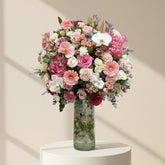 A glass vase filled with a colorful bouquet of pink and white flowers.
