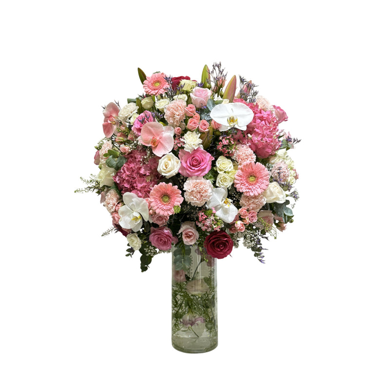 A glass vase filled with a colorful bouquet of pink and white flowers.