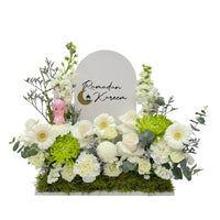 A floral display with white and green flowers, a "Ramadan Kareem" sign, and a small decorative lantern.