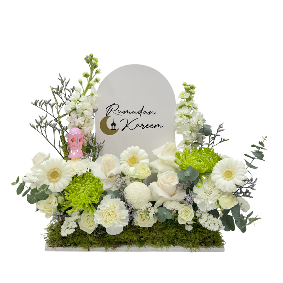 A floral display with white and green flowers, a "Ramadan Kareem" sign, and a small decorative lantern.