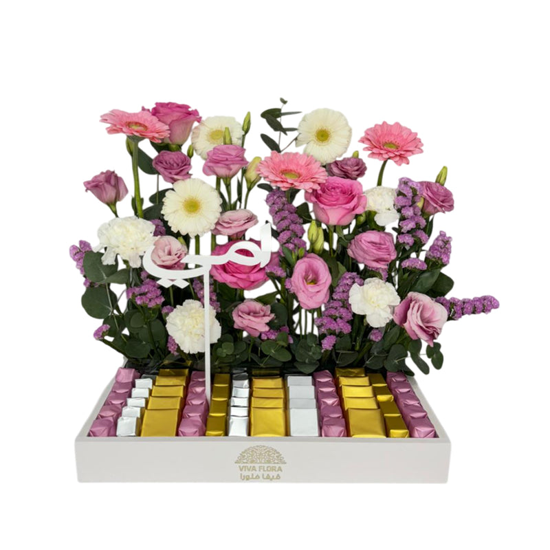 Pink and white flowers with a tray of assorted chocolates.