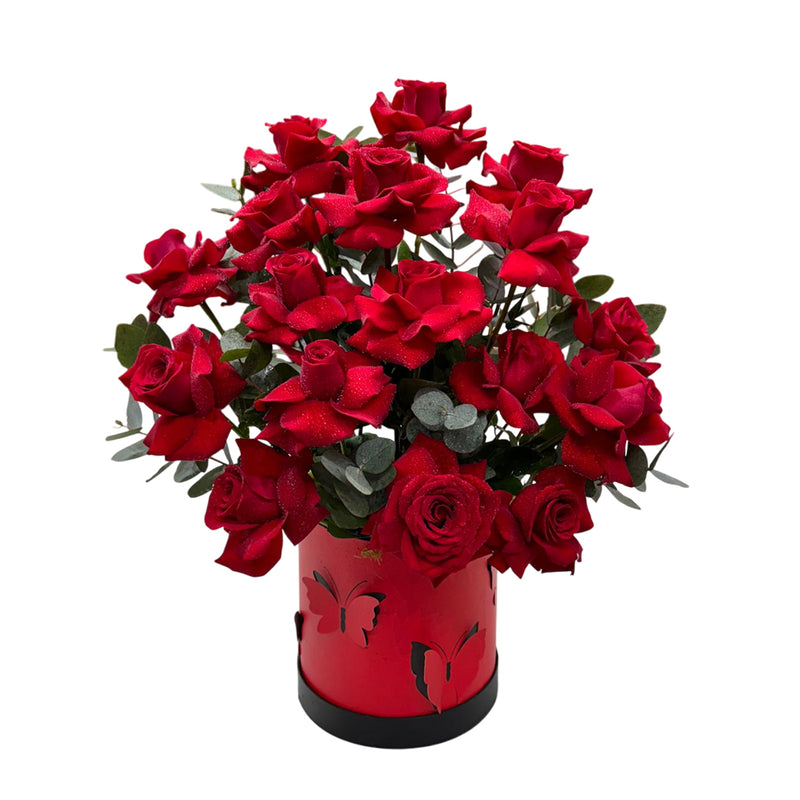 A red box accented with butterflies filled witth red roses and eucalyptus.