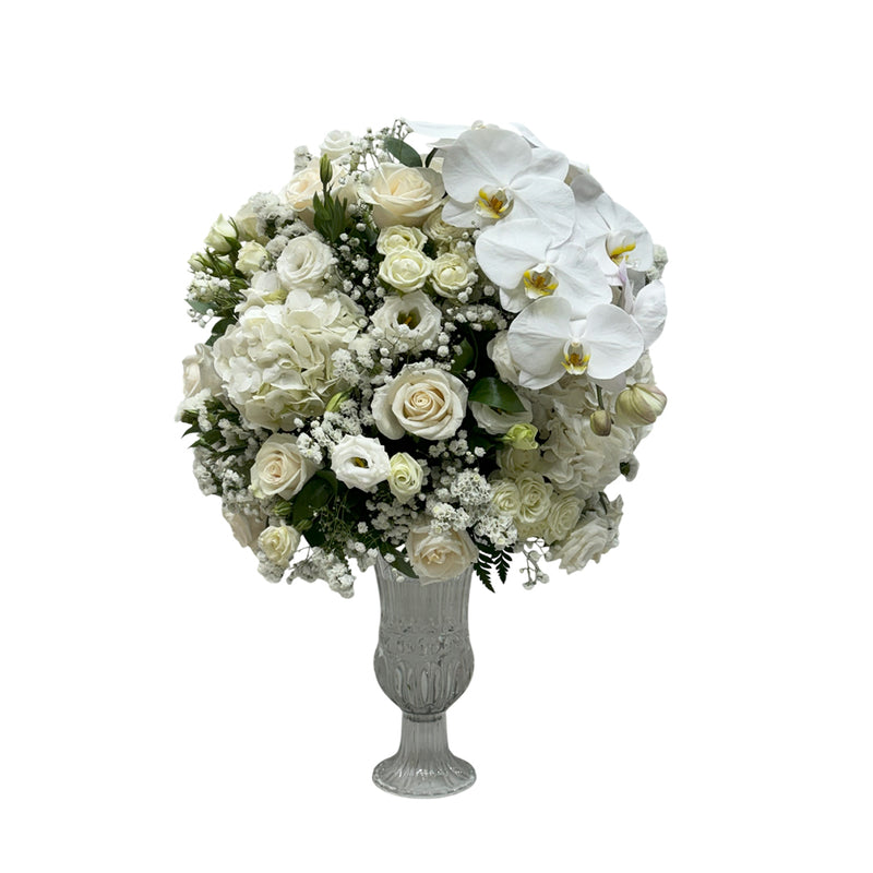 A crystal vase filled with white roses, hydrangeas, orchids, and baby's breath.