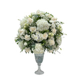 An elegant white bouquet of roses, hydrangeas, and chrysanthemums in a crystal vase.