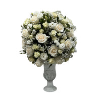 A white flower arrangement in a crystal vase on a white table.