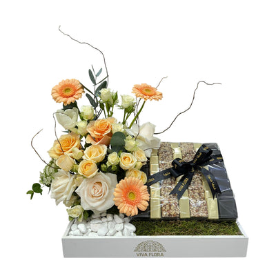Luxury white tray with peach and white roses, gerberas, and 800g of assorted chocolates wrapped in Viva Flora ribbon.