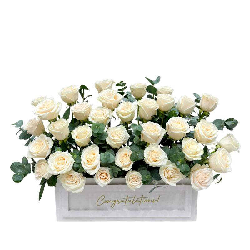 White roses in white rectangular box with “Congratulations” text.