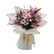 A beautiful bouquet of pink lilies, roses, and chrysanthemums wrapped in white paper with a gold ribbon.