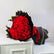 A large bouquet of red roses wrapped in black paper with gold edges, displayed on a white surface against a white background, with a second wrapped bouquet standing behind it.