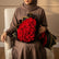 A large bouquet of red roses wrapped in black paper with gold edges, displayed on a white surface against a white background, with a second wrapped bouquet standing behind it.