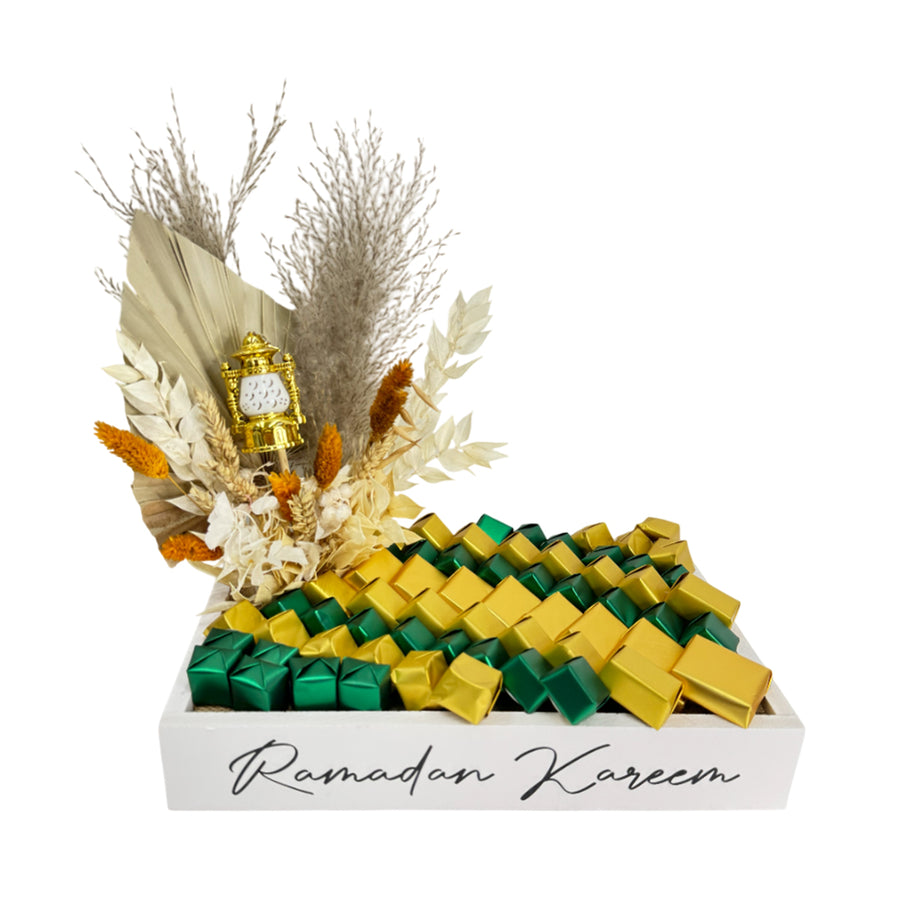  A luxurious Ramadan chocolate tray with gold and green-wrapped chocolates, dried floral decor, and a  lantern. 