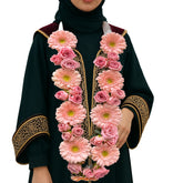 Pink gerbera and rose floral garland necklace on a female graduate in black and gold gown