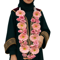 Pink gerbera and rose floral garland necklace on a female graduate in black and gold gown
