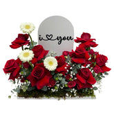 Flower arrangement with red roses, white gerberas, with  "I Love You" sign in middle.