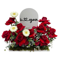 Flower arrangement with red roses, white gerberas, with  "I Love You" sign in middle.