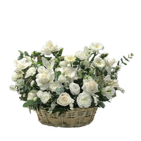 A basket overflowing with white roses, lilies, and other delicate blooms, perfect for sympathy or condolence arrangements.