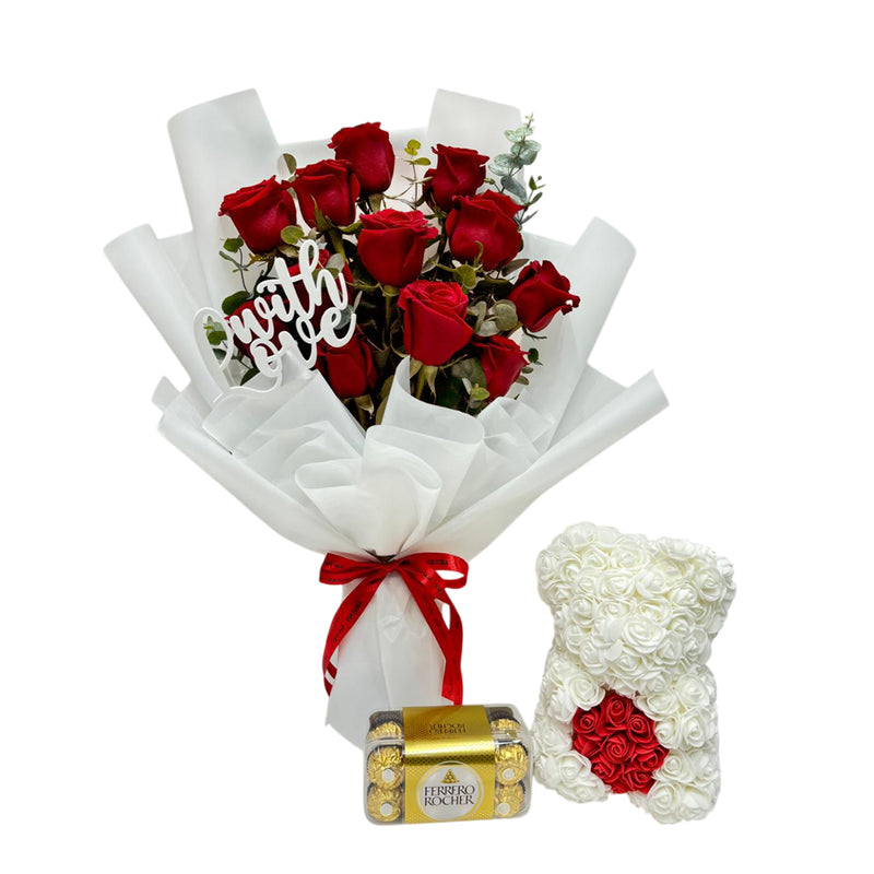 Close-up of red roses bouquet, Ferrero Rocher, and floral teddy bear gift for Valentine’s Day.