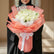 A bouquet of white roses wrapped in sheer coral and white paper with a white ribbon, displayed on a white pedestal against a warm beige background with soft window shadows.