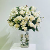 White roses arranged in a clear glass vase with greenery and water buy and in qatar