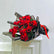 A bouquet of red roses wrapped in black paper with a red ribbon, displayed on a white pedestal against a plain light background.