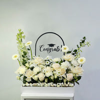Floral arrangement with 'Congrats!' sign on a light gray background