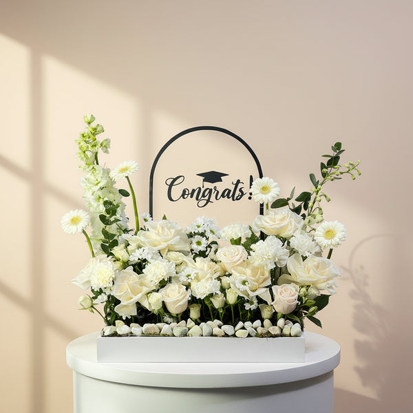 Floral arrangement with 'Congrats!' sign on a light gray background