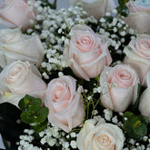 Bouquet of pink roses and baby's breath with green leaves.