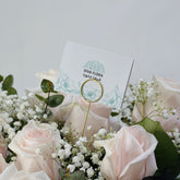 Bouquet of pink roses and white flowers with a VIVA FLORA card in the background.