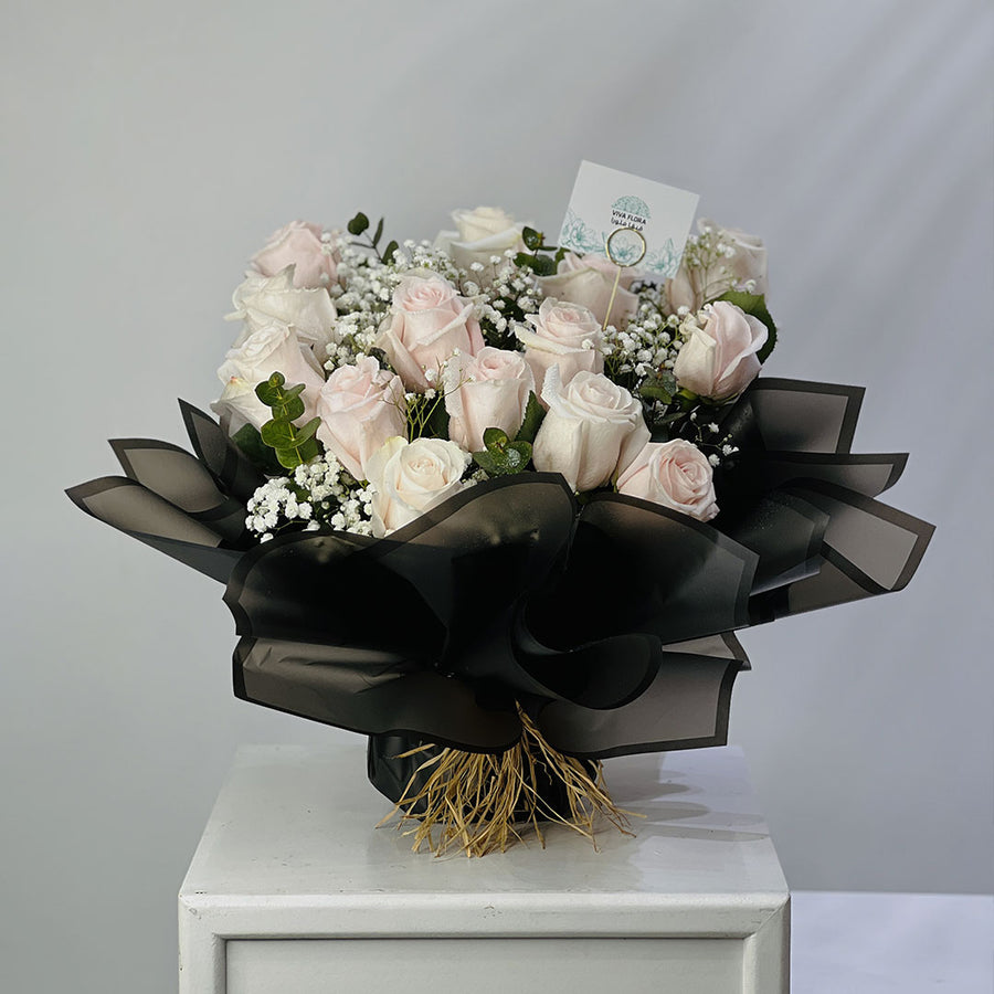 Bouquet of pink roses with black ribbons on a white surface against a gray background