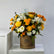 A vibrant floral arrangement in a round brown cardboard box with the brand name 'VIVA FLORA' printed on it, set on a white marble surface against a light gray wall.
