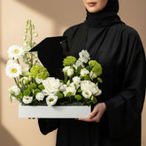 Floral arrangement with a black graduation cap silhouette on a white surface against a light gray background