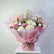A vibrant floral bouquet wrapped in pink tissue paper and tied with a brown twine bow, displayed on a white pedestal against a light gray background.