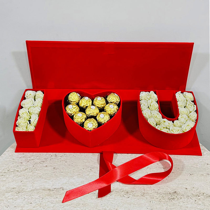 Red gift box with 'I LOVE YOU' arrangement of flowers and chocolates on a light background