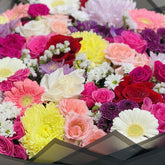 Colorful mixed flower bouquet with roses and chrysanthemums in black wrapping