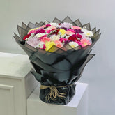 Bouquet of flowers wrapped in black paper on a white surface with a light gray background